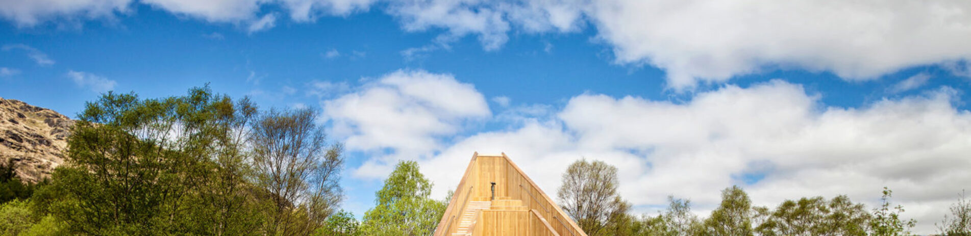 an-ceann-mor-wooden-structure-scenic-art-installation-among-trees-with-blue-sky-and-clouds-above