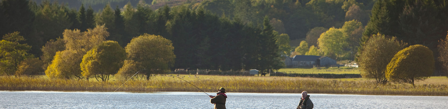 two-men-fishing-from-boat-on-loch-with-hills-and-forests-in-the-background