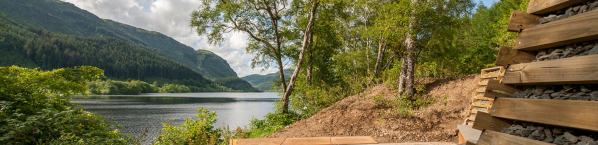 faerie-hollow-scenic-art-installation-platform-of-stone-and-wood-at-edge-of-loch-lubnaig-with-stunning-views-over-forested-shores-and-hills-behind