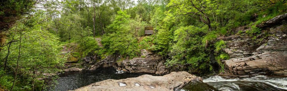 view-of-falls-of-falloch-from-above-the-falls-with-woven-sound-the-scenic-art-installation-visible-among-trees-across-the-water