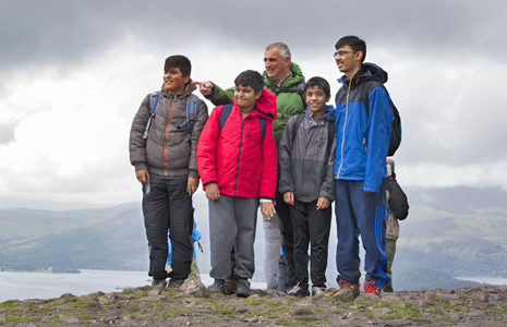 national-park-ranger-in-green-jacket-pointing-in-the-distance-to-group-of-male-students-on-top-of-conic-hill