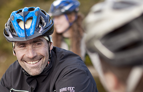 men-with-stubble-in-biking-gear-with-helmet-on-smiling-and-chatting-to-fellow-cyclists