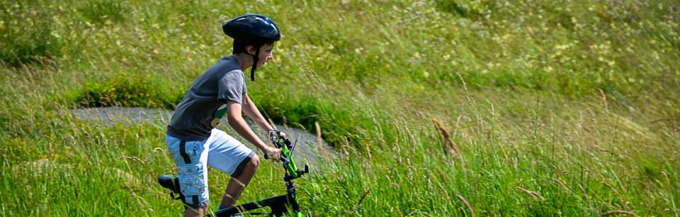 boy-with-helmet-on-cycling-in-high-grass