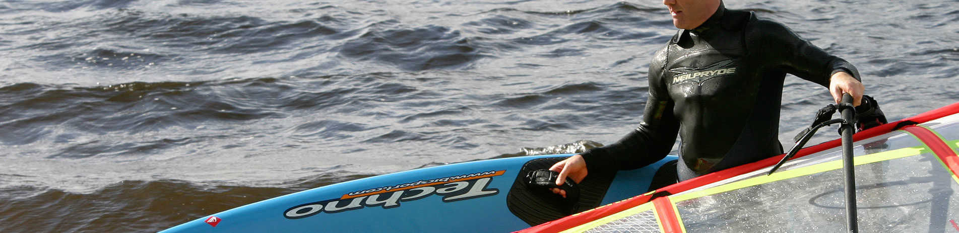 close-up-of-middle-aged-man-in-wetsuit-holding-paddleboard-and-veil-coming-out-of-loch-water