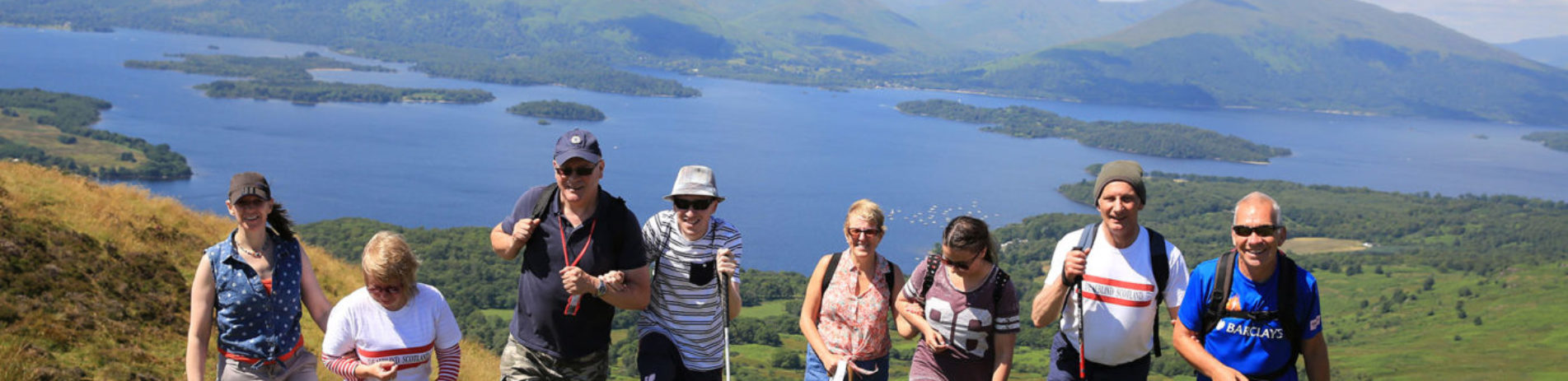 deaf-blind-group-of-men-and-women-walk-up-conic-hill-with-stunning-views-of-loch-lomond-and-islands-behind