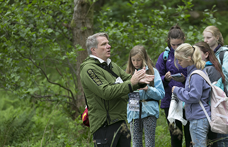 national-park-ranger-chatting-animatedly-to-group-of-girls-in-the-forest