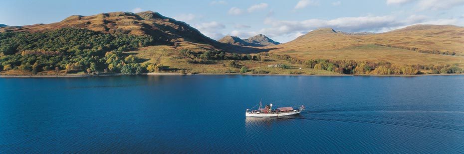 loch-katrine-covered-on-its-shores-by-beautiful-native-woods-part-of-the-great-trossachs-forest-steamship-crossing-waters-leaving-lines-behind