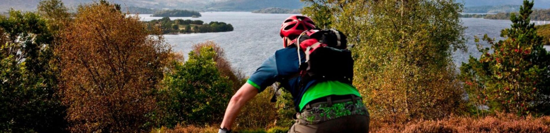 make-cyclist-on-bike-heading-downhill-with-forest-and-loch-lomond-in-the-distance-in-front-of-him