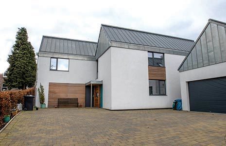 white-contemporary-house-with-steel-grey-roof-and-tall-tree-on-the-left-and-garage-block-on-the-right