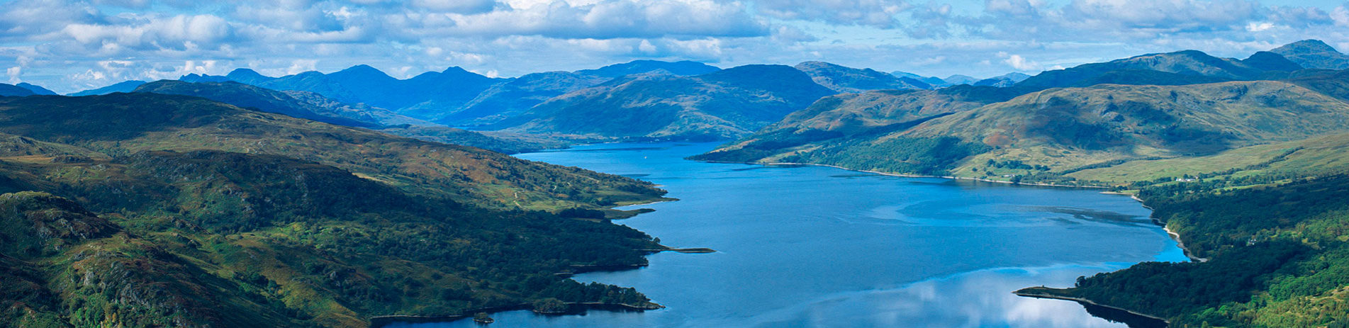 landscape-of-loch-katrine-in-deep-shade-of-blue-surrounded-by-the-forested-trossachs-mountains-and-cloudy-sky-above