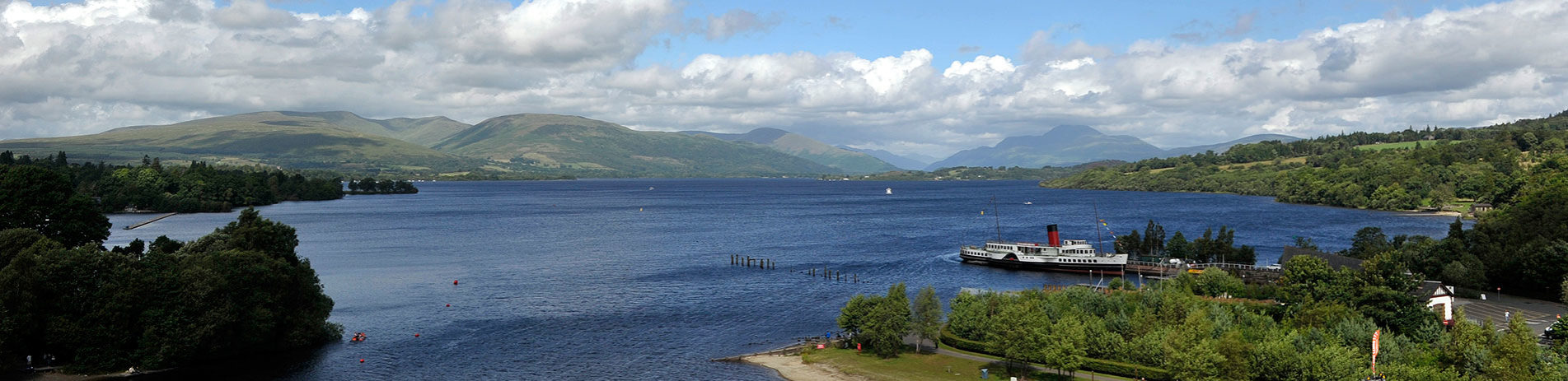 aerial-view-of-loch-lomond-on-sunny-day-with-maid-of-the-loch-steamship-and-ben-lomond-visible-in-the-distance