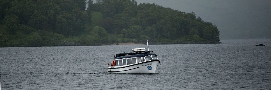 white-waterbus-on-misty-loch-with-wooded-shore-behind