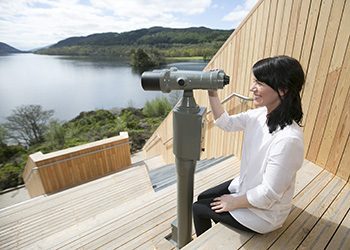 woman-in-white-looking-through-fixed-binoculars-at-an-ceann-mor-scenic-art-installation-over-loch-lomond