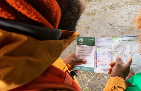 looking over a persons shoulder who is looking and pointing at a map.