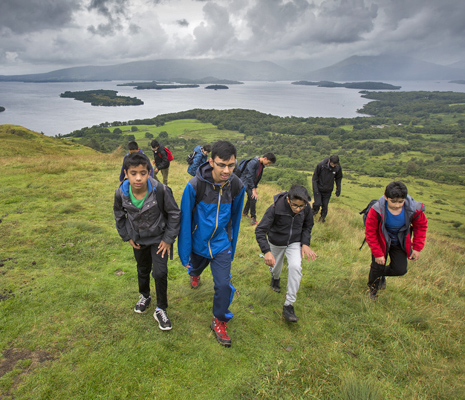group-of-young-male-students-climbing-slopes-of-conic-hill-with-loch-lomond-and-islands-in-the-distance