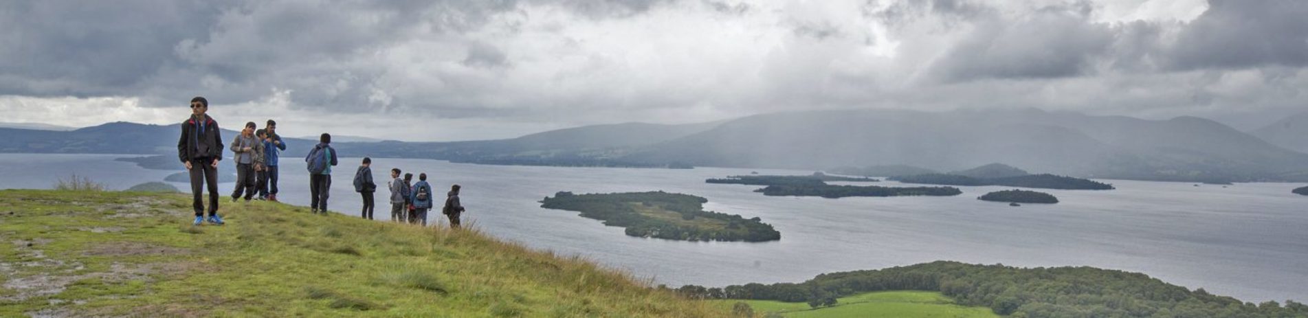 group-of-young-male-students-climbing-slopes-of-conic-hill-with-loch-lomond-and-islands-in-the-distance