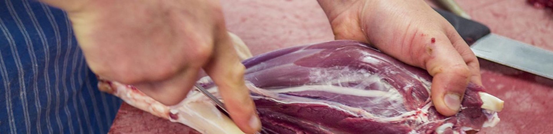 close-up-of-hands-cutting-raw-meat