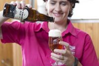 woman-in-pink-t-shirt-pouring-beer-in-glass-and-smiling