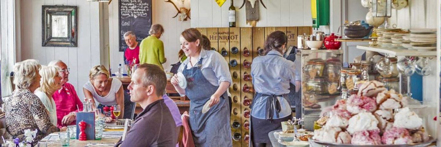 mhor-eighty-four-restaurant-interior-meringues-visible-on-plate-on-right-and-smiling-waitress-attending-to-table-of-men-and-women-on-left-everything-is-very-colourful