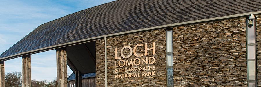 carrochan-building-national-park-headquarters-with-large-logo-prominent-and-blue-skies-above