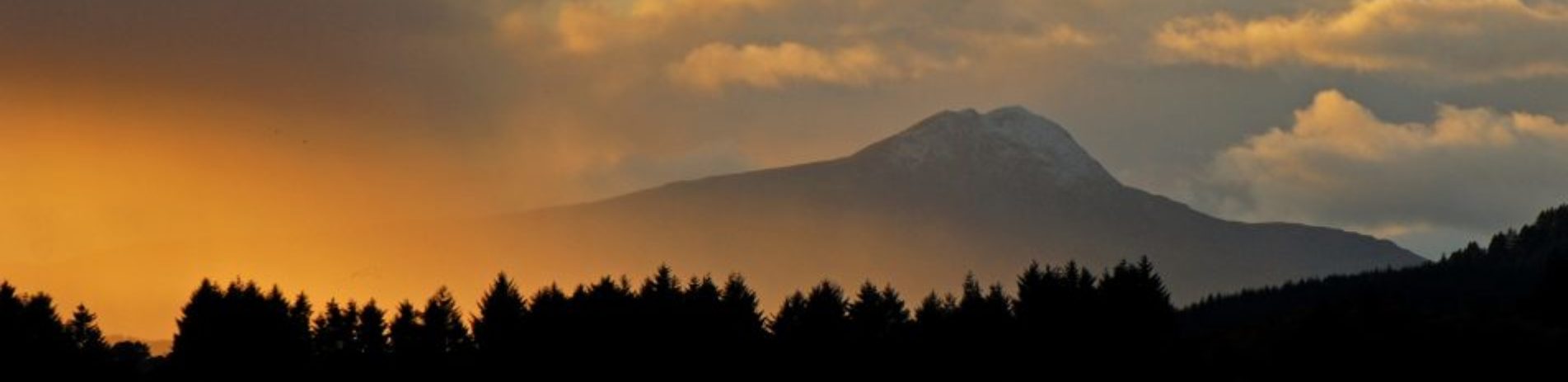 sunset-over-loch-forest-and-mountain-background