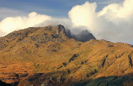 zoom-in-on-ben-arthur-or-cobbler-mountain-in-cowal-area-of-national-park-illuminated-by-sun-with-clouds-above-summit