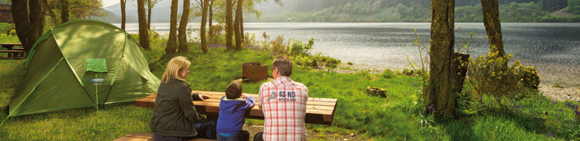 family-at-picnic-table-next to tent-and-loch