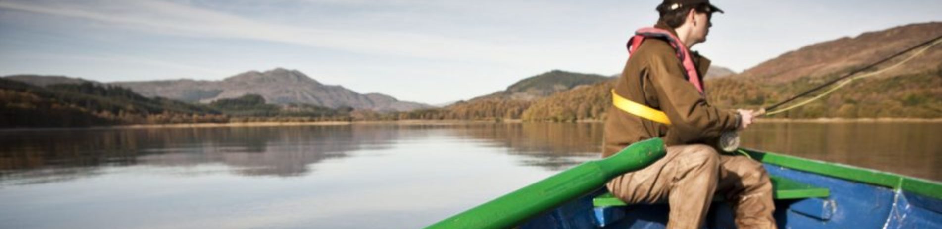 boat-fisherman-on-loch-with-mountain-background