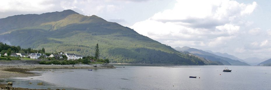 ardentinny-village-on-the-shore-of-loch-long-with-forested-hills-towering-above-and-arrochar-alps-profiling-in-the-distance