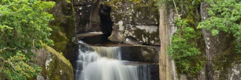 bracklinn-falls-beautiful-water-flow-between-large-blocks-of-rock-surrounded-by-lush-vegetation