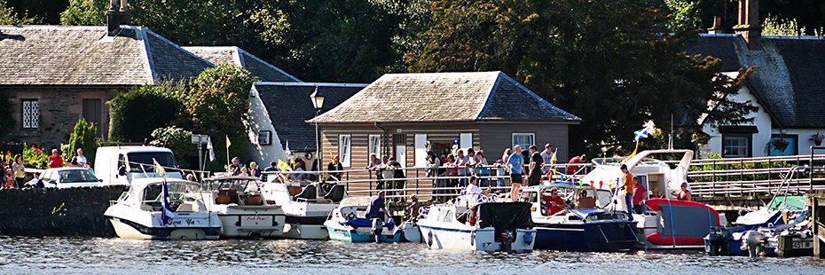 busy-waterfront-moored-boats-and-groups-of-people-outside-houses