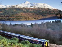 train-crossing-landscape-above-tarbet-with-ben-lomond-towering-above-loch-lomond-in-the-distance