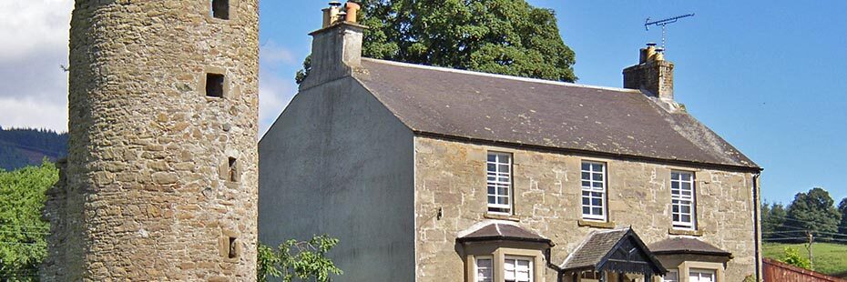 old-victorian-farmhouse-with-medieval-round-tower-next-to-it-in-port-of-menteith-village-blue-skies-summer-day