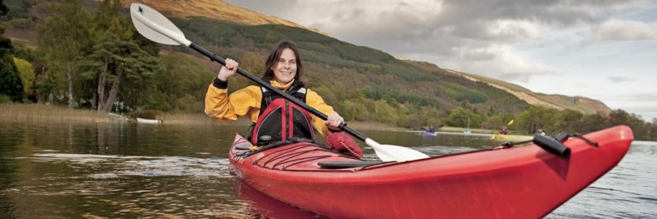 woman-kayaking-tree-covered-mountain-in-background