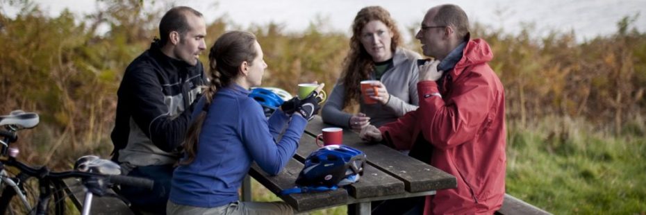 four-people-sitting-at-picnic-bench-with-hot-drinks