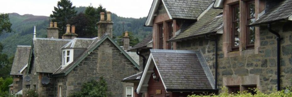 saint-fillans-village-main-street-stunning-victorian-stone-mansions-with-slate-roofs-and-hedge-rows-in-front-forested-hills-behind-on-left