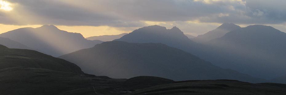 outline-of-arrochar-alps-hills-especially-cobbler-in-sunset-light-through-clouds-panorama-from-beinn-dubh-part-of-luss-hills