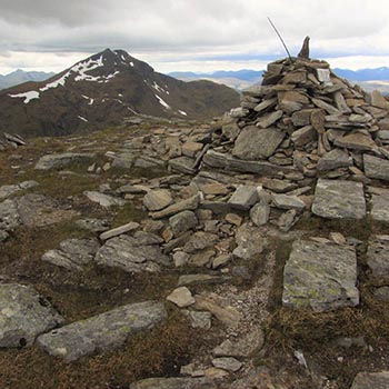 ben-oss-summit-cairn-of-stones-with-ben-lui-peak-behind-in-the-distance-cloudy-sky