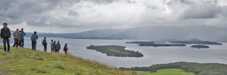 group-of-young-male-students-climbing-slopes-of-conic-hill-with-loch-lomond-and-islands-in-the-distance