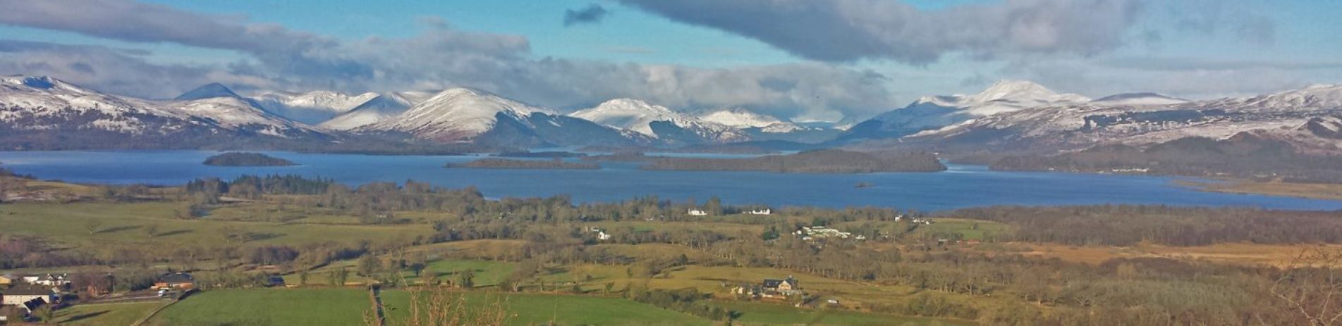 panorama-of-loch-lomond-islands-and-surrounding-hills-covered-by-snow-with-gartocharn-village-and-farmland-in-foreground-seen-from-dumpling-hill