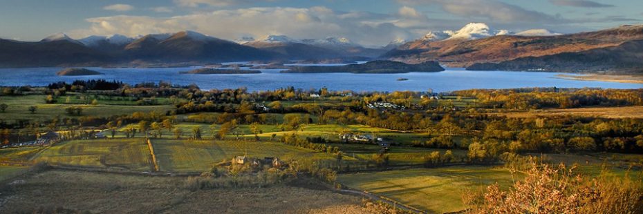 panorama-of-loch-lomond-islands-and-surrounding-hills-partly-covered-by-snow-with-gartocharn-village-and-farmland-in-foreground-seen-from-dumpling-hill