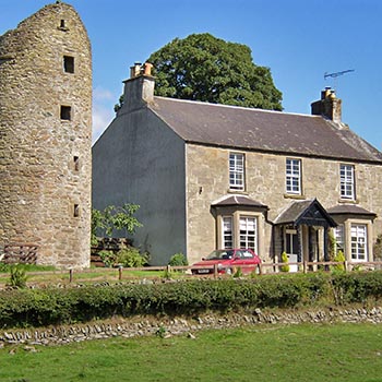 old-victorian-farmhouse-with-medieval-round-tower-next-to-it-in-port-of-menteith-village-blue-skies-summer-day