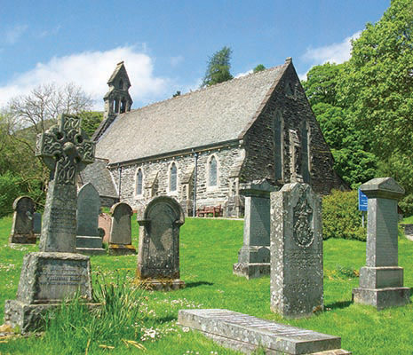 balquhidder-church-and-graveyard-with-old-celtic-cross-on-left-blue-skies-and-lush-trees-surrounding-it
