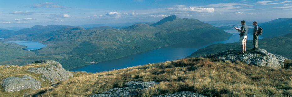 two-hillwalkers-on-a-mountain-summit-overlooking-a-loch