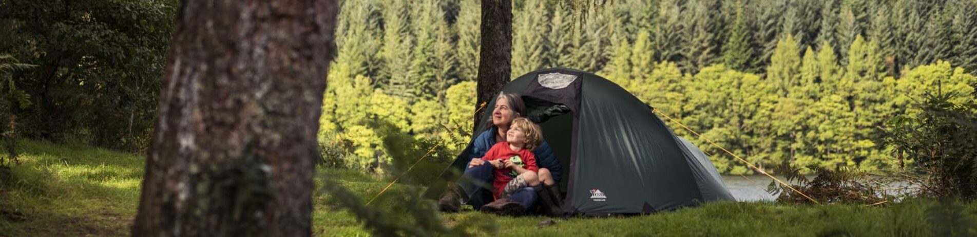 woman-holding-young-boy-at-tent-entrance-at-three-lochs-forest-drive