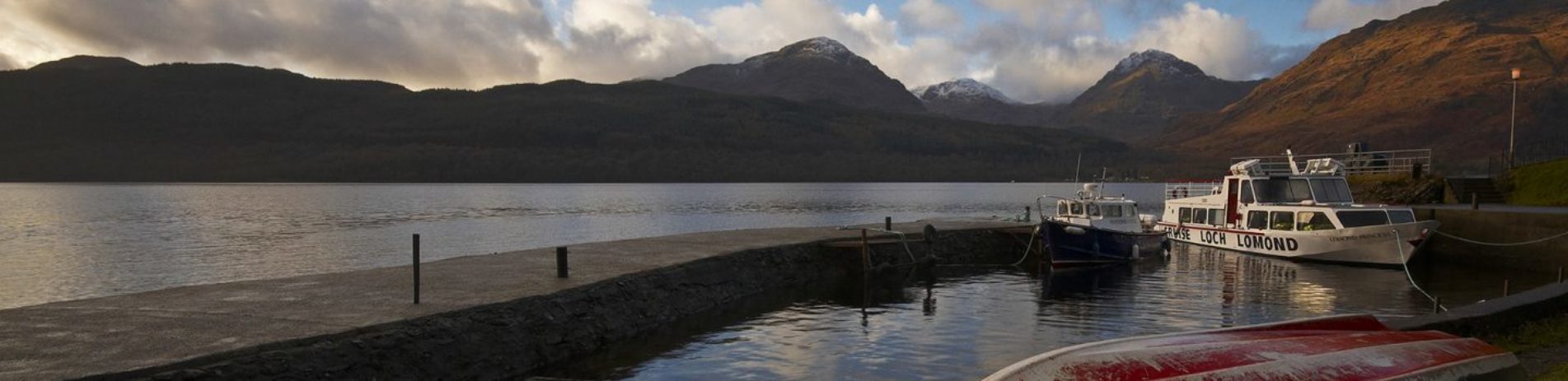 pier-and-boats-at-inversnaid-on-loch-lomond-with-arrochar-alps-hills-in0-the-distance