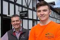 two-men-of-different-ages-part-of-callander-youth-project-smiling-at-camera-outside-bridgend-cafe-in-callander