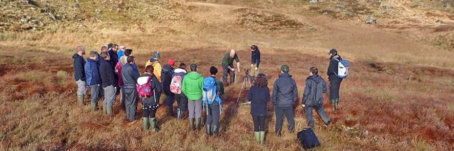 man-and-woman-demonstrating-taking-a-peat-core-in-front-of-group