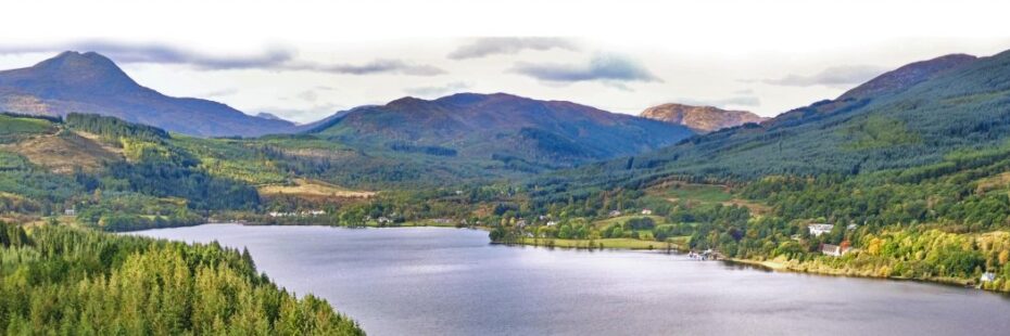 aerial-view-of-loch-ard-surrounded-by-forests-and-with-ben-lomond-towering-above-in-the-distance