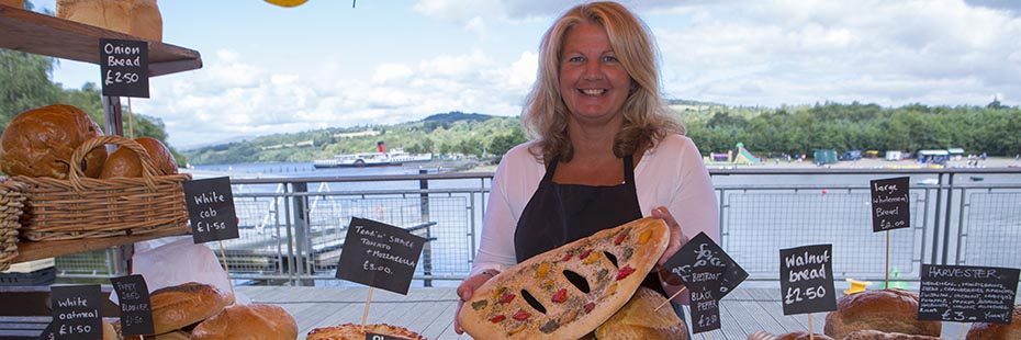 woman-smiling-and-holding-focaccia-bread-at-food-festival-stall-next-to-loch-lomond